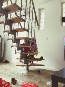 Des artisans rénovent le salon d’une maison habitée tandis que les meubles sont protégés par des bâches.